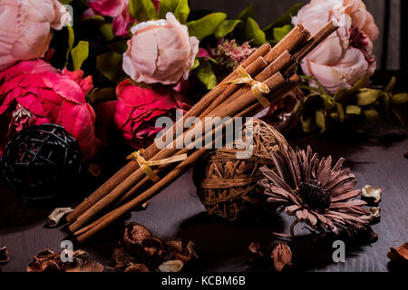 Gemahlener Zimt, Zimtstangen, mit einem Tablett mit einem Bogen auf einem floral background im rustikalen Stil verbunden. Selektive konzentrieren. Essen Konzept. Jahrgang zu Stockfoto