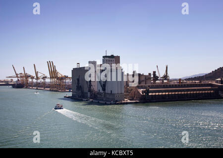 Luftaufnahme von einer Tour Boot mit Menschen verlassen den Hafen von Barcelona. Versand/Logistik im Hintergrund. Es ist toll, kommerzielle Bedeutung Stockfoto