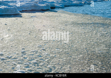 Schmelz Eisbrocken floating in Wasser in der Nähe von frozen Shore. Stockfoto