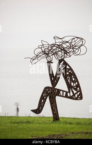 Outdoor Metall Skulptur von stilisierten Mann sitzt im Feld Stockfoto