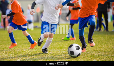 Kinder-Fußball-Fußball-Spieler mit Ball laufen. Fußballer treten Fußballspiel auf dem Spielfeld. Junge Teen Fußballspiel. Jugend-Sport-Hintergrund Stockfoto