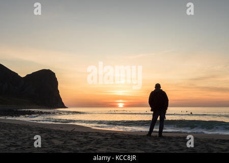 Silhouette eines Mannes an den schönen Sonnenuntergang auf der unstad entfernt. Surfer im Hintergrund Stockfoto