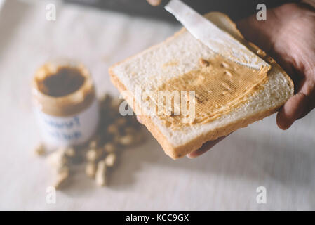 Verbreitung Peanut Butter auf Brot Stockfoto