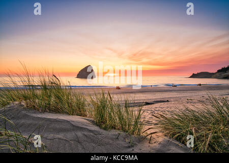 Die Sonne untergeht über dem Haystack Rock in Cape Kiwanda, Pacific City, Oregon, USA Stockfoto
