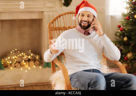 Fröhlicher Mann in santa hut, am Telefon zu sprechen Stockfoto