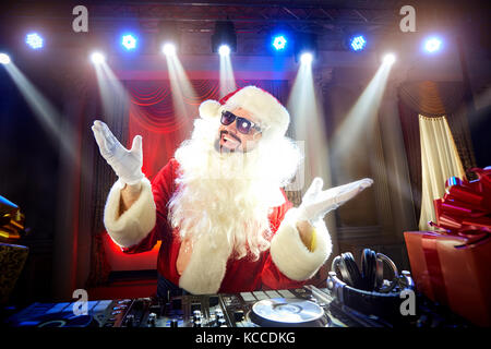 Funny santa dj Mixes in den Strahlen des Lichts Musik. Stockfoto