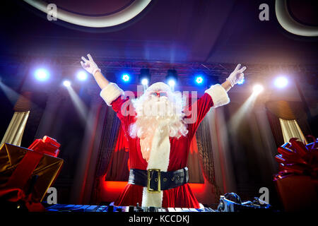 Funny santa dj Mixes in den Strahlen des Lichts Musik. Stockfoto