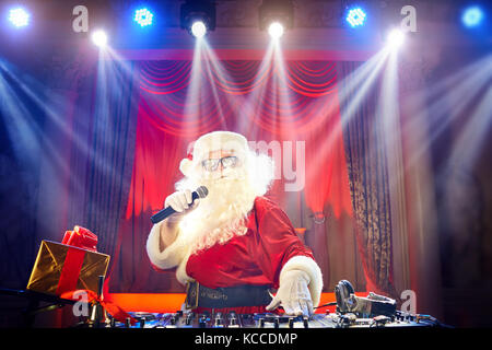 Funny santa dj Mixes in den Strahlen des Lichts Musik. Stockfoto