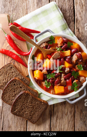 Eintopf mit Rindfleisch, Kürbis, rote Bohnen, Tomaten und Chili close-up in einem Topf auf den Tisch. Senkrechte Draufsicht von oben Stockfoto