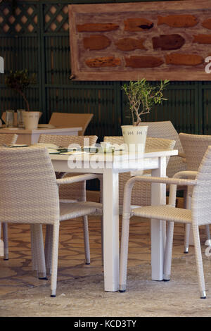 Tische und Stühle für ein Abendessen in einem Restaurant oder Taverne in Griechenland eingestellt. Stockfoto