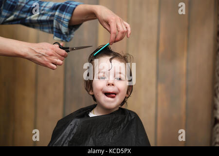 Ein kleiner Junge ist in hellen die Emotionen der Friseur auf getrimmt Stockfoto