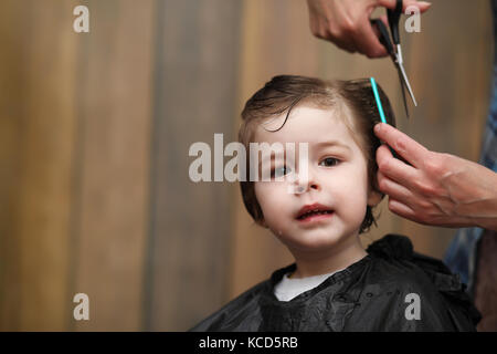 Ein kleiner Junge ist in hellen die Emotionen der Friseur auf getrimmt Stockfoto