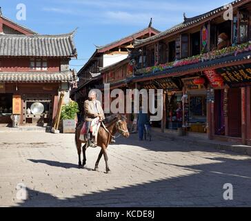 Shuhe Old Town Welterbestätte, Provinz Yunnan, China. Naxi ethnische Menschen Pferde und Händler handeln uralte Kulturstätte Straßenszene in Lijiang Stockfoto