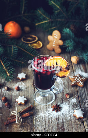 Glühwein im Glas mit Preiselbeeren und Gewürzen dekoriert mit orange. Weihnachten Trinken. Essen urlaub Konzept Stockfoto
