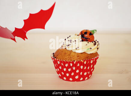 Cupcake dekoriert mit Sahne und Marzipan Kürbis an Halloween auf dem beigen Hintergrund Stockfoto