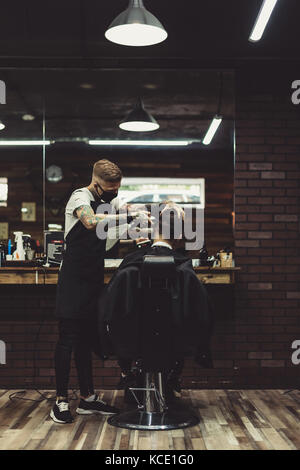 Stilvolle Mann bei der Arbeit mit Kunden im Salon Stockfoto