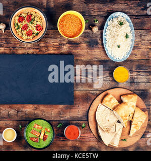 Sortierte indisches Essen auf hölzernen Hintergrund. Gerichte und Vorspeisen der indischen Küche. curry, Butter Huhn, Reis, Linsen, Palak Paneer, Samosa, Naan, Stockfoto