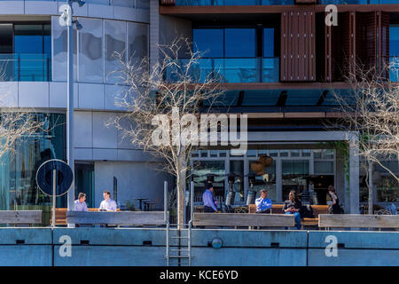 Geschäftsleute genießen die Zeit draußen in der Sonne in Barangaroo mit Blick auf den Hafen von Sydney, NSW, Australien Stockfoto