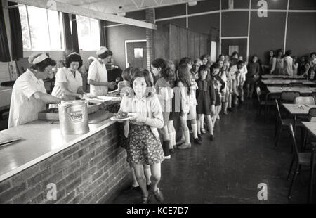 1970s, historisches Bild, das junge Mädchen an der Langbourne Primary School zeigt, die sich innen für ihr Schulessen anstellen (Mittagessen), Dulwich, London, SE21, England, VEREINIGTES KÖNIGREICH. Stockfoto