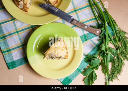 Pfannkuchen Pie mit Pilzen und Hühnerfleisch, mit Käse überbacken auf der grünen Platte. Stück Pfannkuchen, Kuchen auf der grünen Platte mit Kräuter: Dill, grüne Zwiebeln, Par Stockfoto