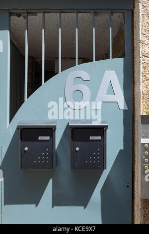 Zwei graue Metall mailboxe mit Schatten auf der blauen Wand Sicherheit Grill und 6 a Stockfoto