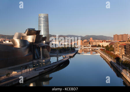 Blick von der Puente de la Salve Brücke entlang des Flusses Nervion Vergangenheit das Guggenheim Gebäude in Richtung Westen von Bilbao bei Sonnenaufgang, Bilbao, Vizcaya, Sp Stockfoto