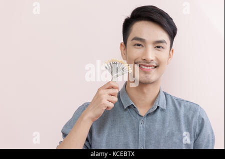 Asiatische Mann lächelnd, während sie Zahn Farbmuster in seiner Hand. Zahnpflege- und Wartungskonzept Stockfoto
