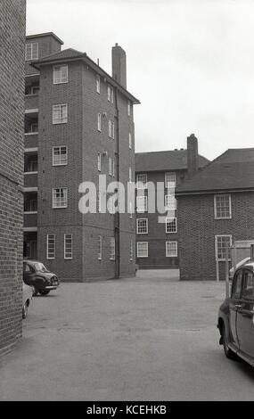 1960, historische, mehrere Autos der Ära abgestellt - Straße, an der Rückseite eines Blocks von Gemeindewohnungen, London, England. Stockfoto