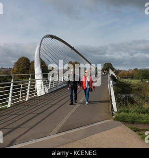 An einem sonnigen Herbsttag, Ansicht von Menschen zu Fuß über die Millennium Bridge, eine moderne Fußgängerbrücke & Radweg über den Fluss Ouse, York, England, UK. Stockfoto