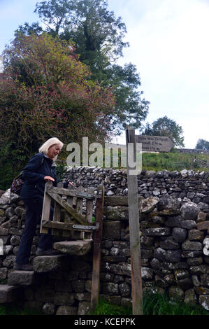 Lone Woman Hiker Climbing Stone Stile auf dem Dales Way Wanderweg zwischen Grassington & Burnsell in Wharfedale, Yorkshire Dales National Park, Stockfoto