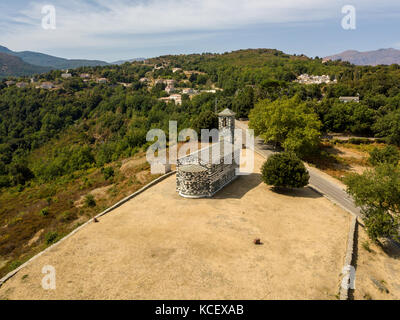 Luftaufnahme der Kirche von San Michele de Murato, Glockenturm und Apsis. Umgeben von einem Platz mit Bäumen. Nördliches Korsika. Frankreich Stockfoto