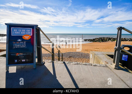 West Bay, Dorset, Großbritannien. 5. Okt 2017. UK Wetter. 2 Minuten Strand Reinigung Zeichen, Leute zu veranlassen, bis Wurf auf Ihren Besuch auf der Schritte zum West Beach an einem Tag des warmen Herbst Sonnenschein und blauer Himmel an der West Bay in Dorset. Photo Credit: Graham Jagd-/Alamy leben Nachrichten Stockfoto