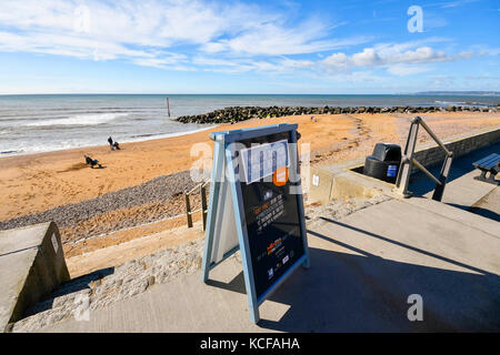 West Bay, Dorset, Großbritannien. 5. Okt 2017. UK Wetter. 2 Minuten Strand Reinigung Zeichen, Leute zu veranlassen, bis Wurf auf Ihren Besuch auf der Schritte zum West Beach an einem Tag des warmen Herbst Sonnenschein und blauer Himmel an der West Bay in Dorset. Photo Credit: Graham Jagd-/Alamy leben Nachrichten Stockfoto