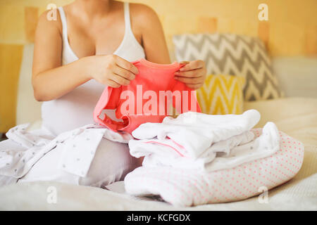 Schwangere Frau ist bereit für die entbindungsklinik Verpackung Babykleidung Stockfoto