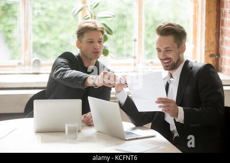 Zwei männliche executive Mitarbeiter suchen auf der Marketing Plan Dokument. positive Projekt Manager und ceo die Diskussion von Möglichkeiten, Planung neue Bus Stockfoto