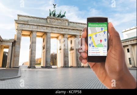 Nahaufnahme der Hand Suche einer Person Restaurants auf seinem GPS-Karte mit Navigation Zeiger Stockfoto