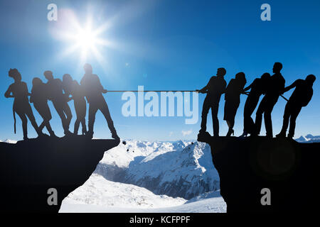 Silhouette von Menschen Tauziehen Spielen des Krieges auf einer Klippe Stockfoto