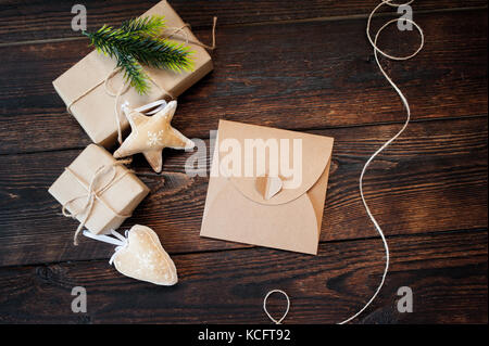 Weihnachten Zusammensetzung der Geschenk Kraftpapier Boxen, textile Spielwaren und Netzkabel Rahmen auf Holz- Hintergrund Stockfoto