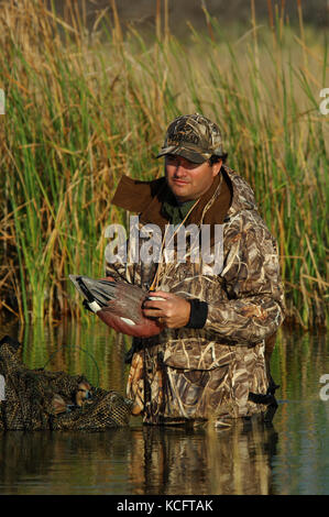 Eine Ente, Hunter in der Tarnung legt seine Jagd Lockvögel in einem South Texas Marsh Stockfoto