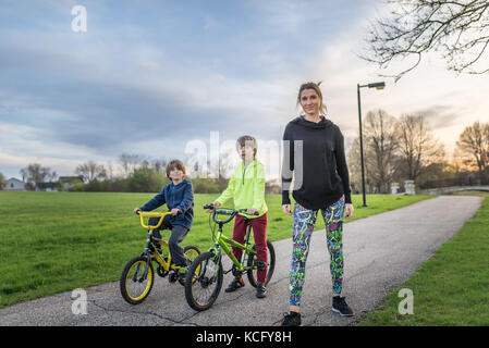 Chicago, IL, USA, 16. April 2017: Mutter mit ihren zwei Kindern auf dem Fahrrad im Park, für die redaktionelle Nutzung nur Stockfoto
