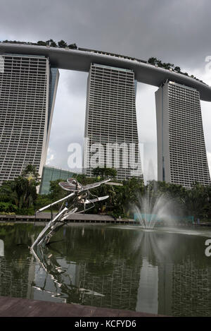 Das Marina Bay Sands Hotel vom Silver Garden auf dem Gelände der Gardens by the Bay in Singapur. Die silberne Statue ist von einer Libelle in D Stockfoto