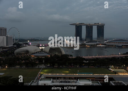 Auch das muschelförmige Esplanade Theatre by the Bay und das Padang. In der Abenddämmerung über Singapur und Marina Bay. Im Vordergrund ist der Padang. Stockfoto