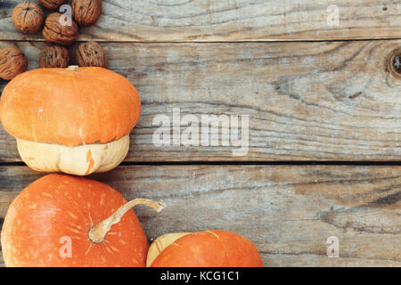 Herbstliche Hintergrund mit Kürbissen und die Muttern an der alten Holztisch Stockfoto