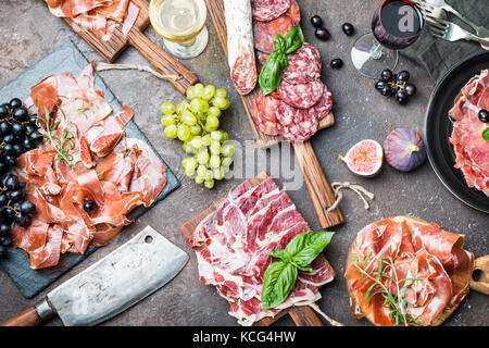 Verschiedene Arten auf Schneiden boardes mit Feigen, Trauben und Wein jamon. parmaschinken Hamon auf hölzernen Hintergrund mit Kopie Raum, Ansicht von oben. Jamon Serrano ibe Stockfoto