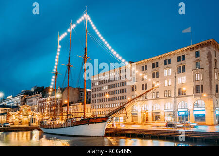 Helsinki, Finnland. Alte hölzerne Segelboot Schiff Schoner ist mit der Stadt pier, Steg vertäut. ungewöhnliche Cafe Restaurant im Stadtzentrum in Beleuchtung in Ev Stockfoto