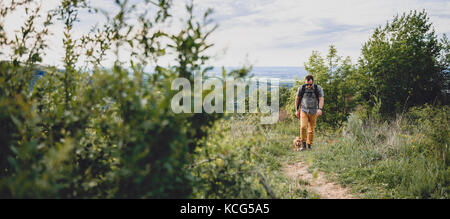 Mann mit Hund auf einem Wanderweg auf dem Berg Stockfoto