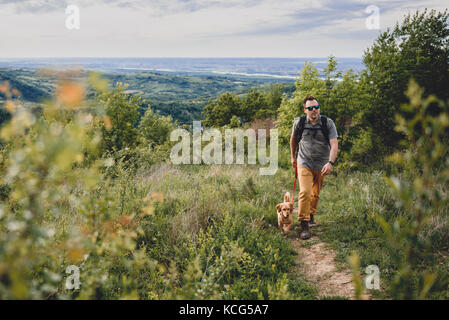 Mann mit Hund auf einem Wanderweg auf dem Berg Stockfoto