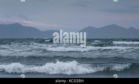 Wellen in den Strand mit den Bergen von Snowdonia im Hintergrund rhosneigr Strand, Insel Anglesey, North Wales, UK Stockfoto