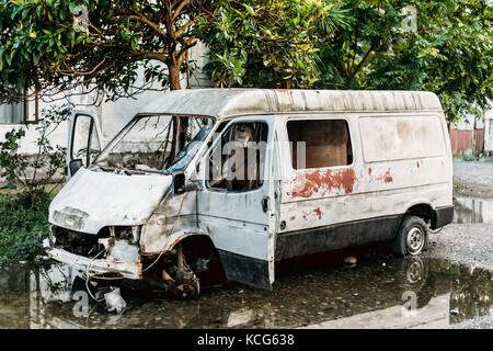 Alte kaputte abgestürzt Rusty minibus Auto in Stadt verlassen. autowrack Stockfoto