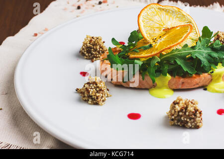 Lachssteak mit Orangensauce, Rucola und Orangenscheiben Stockfoto